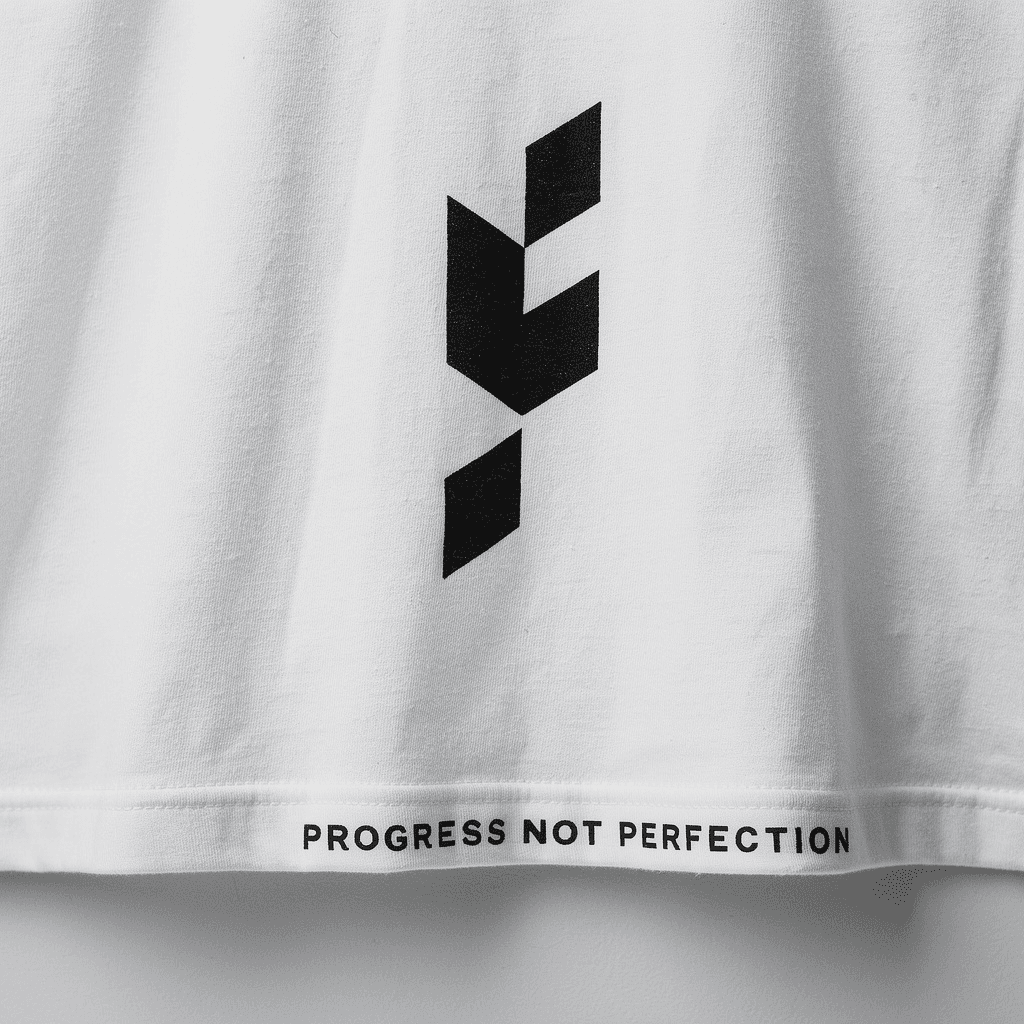 Close-up of a white FitalityWear tee printed with Progress not perfection