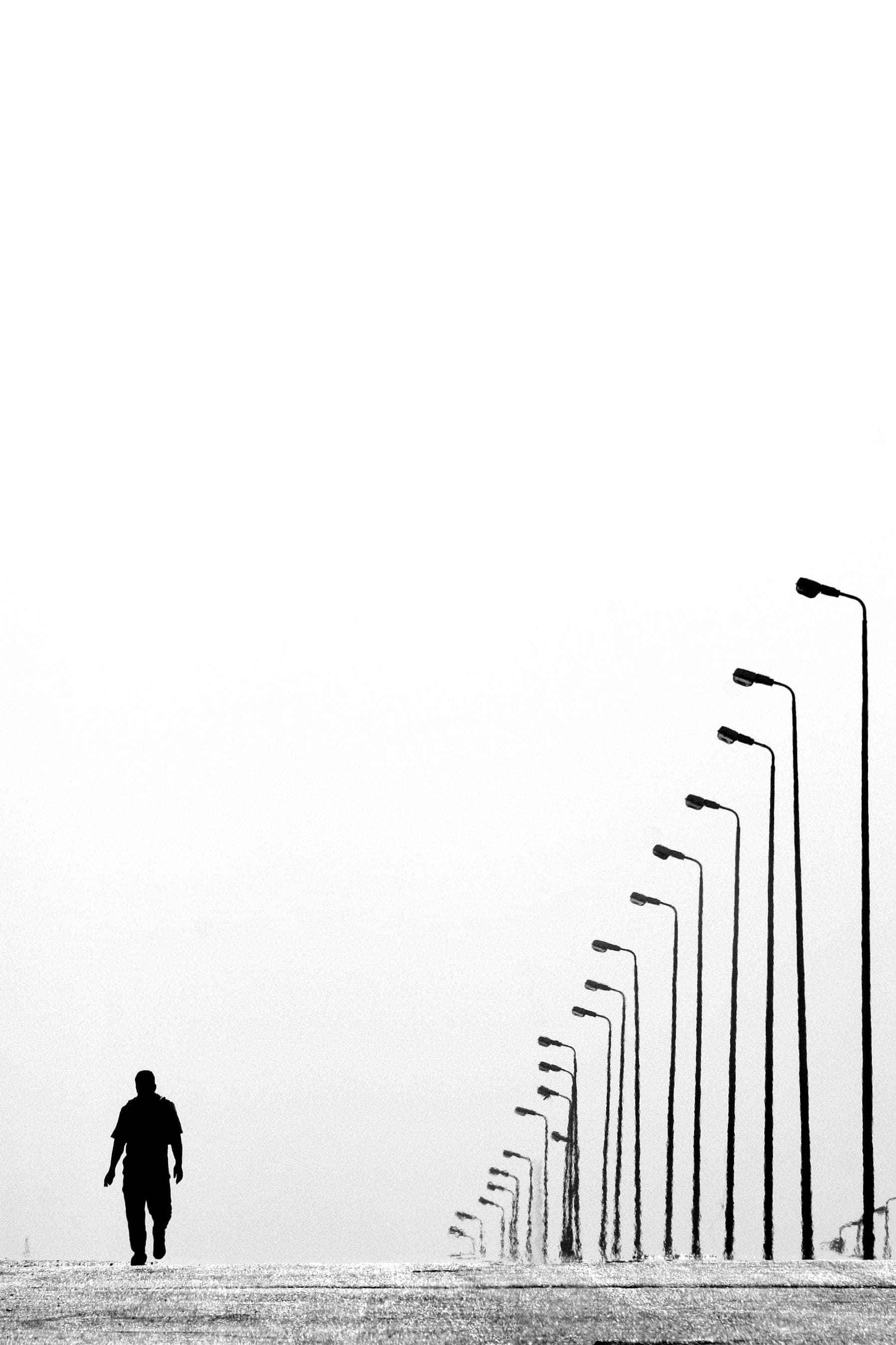 A lone figure walking along a row of streetlights